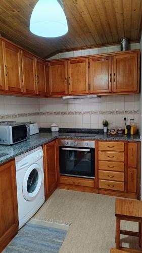 a kitchen with wooden cabinets and a washer and dryer at Casa do Galvão -Turismo Rural - Serra da Estrela in Aguincho