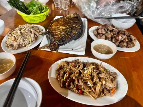 a wooden table with plates of food on it at Hang Mua Eco Garden in Xuân Sơn