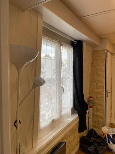 uma janela num pequeno quarto com um candeeiro em Paris roquette em Paris