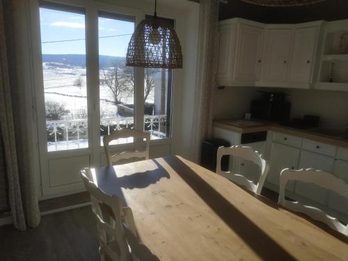 une cuisine avec une table et des chaises en bois ainsi qu'une fenêtre dans l'établissement GRAND APPARTEMENT COSY DANS MAISON DE CAMPAGNE, à Saint-Pierre