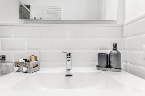 a white kitchen counter with a bottle and a sink at Sweethome Marconi in Rome