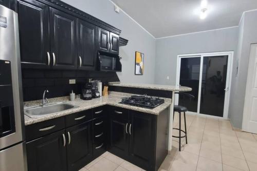 a kitchen with black cabinets and a sink at Vivienda familiar in San Miguel