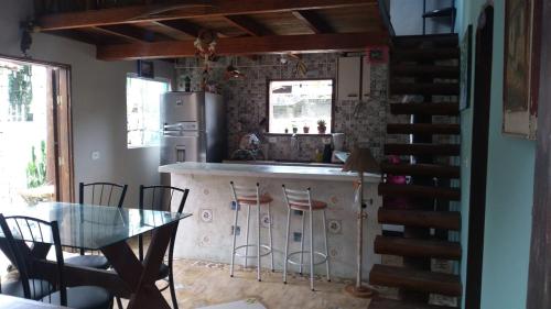 a kitchen with a bar with stools and a table at Chalé Claudio Rambo in Ilhabela