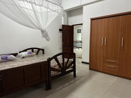 a bedroom with a bed and a wooden cabinet at Naturus Villa Thalpitiya in Panadura
