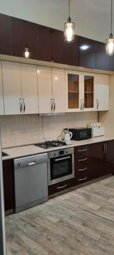 a kitchen with white cabinets and a stove top oven at City Center Apartment in Kutaisi