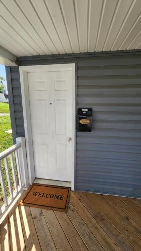 - une porte blanche avec un panneau de bienvenue sur une terrasse couverte dans l'établissement Apartment Retreat, à Roanoke