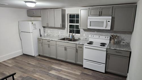 une cuisine équipée d'appareils blancs et de placards gris dans l'établissement Apartment Retreat, à Roanoke