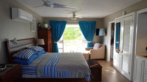 a bedroom with a bed and a window with blue curtains at Point Village in Negril