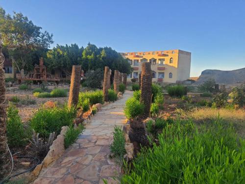 a garden with a stone path in front of a building at Oasis Panorama Hotel in Bawiti