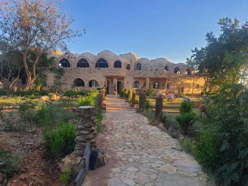 a stone building with a path in front of it at Oasis Panorama Hotel in Bawiti