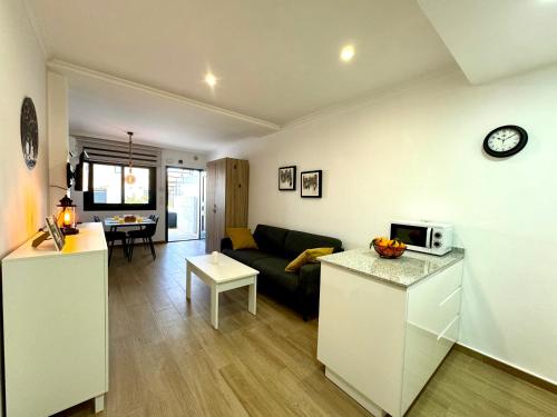 ein Wohnzimmer und eine Küche mit einer Couch und einem Tisch in der Unterkunft La Zenia Boulevard & Beach House in Orihuela