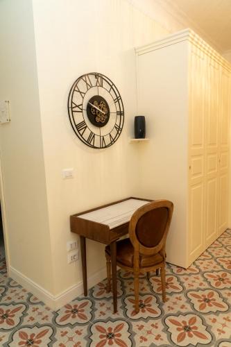 a clock on the wall above a table and a chair at Domus Sibyllina, Palazzo Cavalcanti in Naples