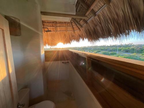 a bathroom with a toilet and a straw roof at Casa Gitana in Chamuscadero