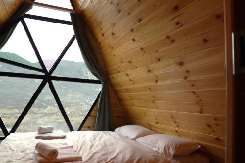a bed in a room with a large window at Ramona in Ambrolauri