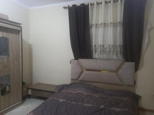 sypialnia z łóżkiem i oknem z zasłonami w obiekcie Rum Bedouin House w mieście Disah