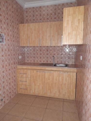 a kitchen with wooden cabinets and a sink at Atom Height Apartments in Tema