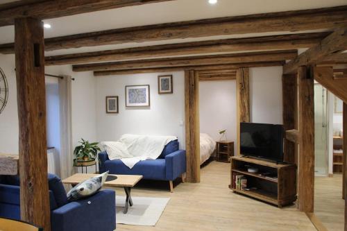 uma sala de estar com um sofá azul e uma televisão em La p'tite maison em Orschwihr