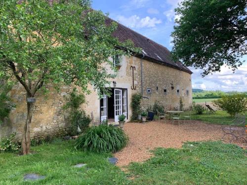 ein altes Steingebäude mit einem Baum davor in der Unterkunft Maison au cœur du Perche in Val-au-Perche