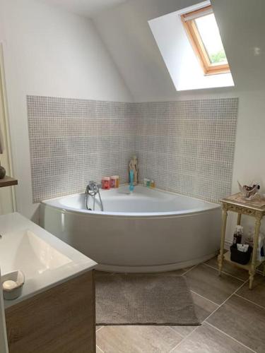 une baignoire blanche dans une salle de bain avec un puits de lumière dans l'établissement Maison au cœur du Perche, à Val-au-Perche