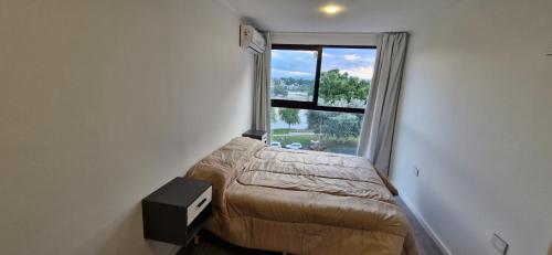 a small bedroom with a bed and a window at Vivisierras, Piso 4 frente al lago Centro Villa Carlos Paz, pileta privada, vista panorámica in Villa Carlos Paz
