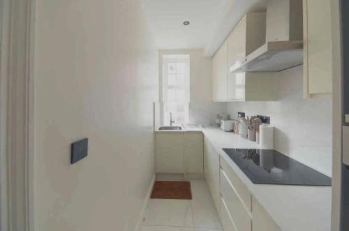 una cucina bianca con mobili bianchi e un lavello di Entire Luxury apartment in Greater London a Londra