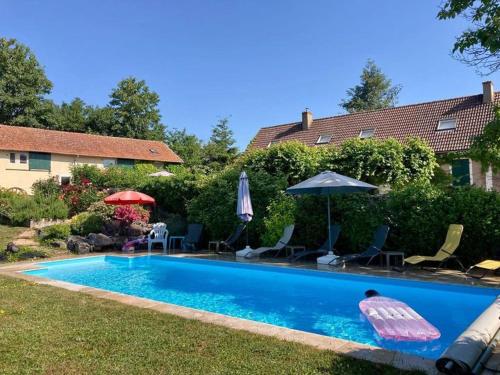 a swimming pool with chairs and an umbrella and an inflatable at Gites La Tourelle in Uxeau