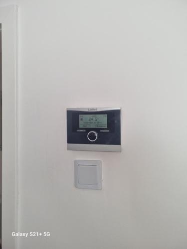 an electronic device on a white wall with a clock at Exklusives Apartment nah S-Bahn in Bochum