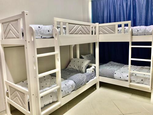 two white bunk beds in a room at Rest N Ramble Hostel Near ADCB Metro Station in Dubai