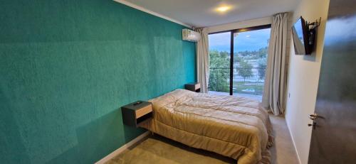 a bedroom with a bed and a green wall at Piso 3 frente al lago, centro Villa Carlos Paz pileta privada in Villa Carlos Paz