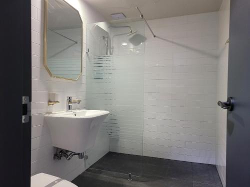 a white bathroom with a sink and a mirror at Romio Motel in Gwangju