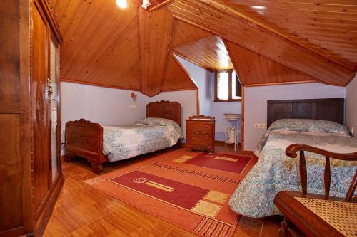 a bedroom with two beds in a room with wooden ceilings at Casa Rural Casa Capión in Villaviciosa