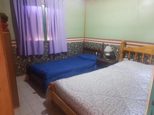 two beds in a bedroom with purple curtains at Cabañas del Sol in Vista Flores