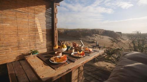 una mesa con platos de comida en la parte superior de un balcón en Narakan Cabo Polonio, en Cabo Polonio