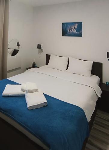 a large white bed with two towels on a blue blanket at Flory Holiday in Sibiu