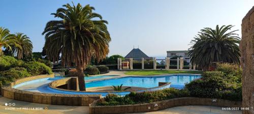 una piscina con palmeras y un edificio en Precioso depto vista al mar Concon Condominio Tipo Resort 2 dormitorios en Concón