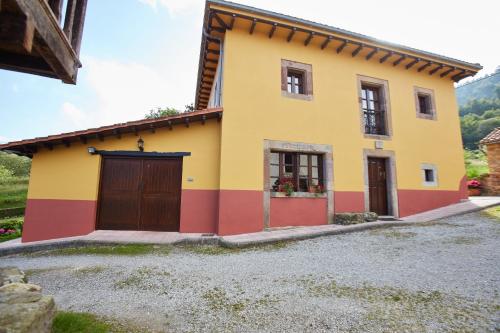 a yellow and red house with a garage at Casa Rural Casa Capión in Villaviciosa