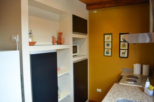 una cocina con paredes amarillas y estanterías blancas en Catalina Apart en San Salvador de Jujuy