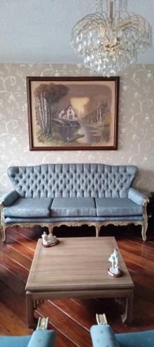 a blue couch in a living room with a chandelier at Pamplona apartment in Ambato
