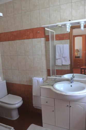 a bathroom with a sink and a toilet and a mirror at Casa da Aguada in Lajes do Pico