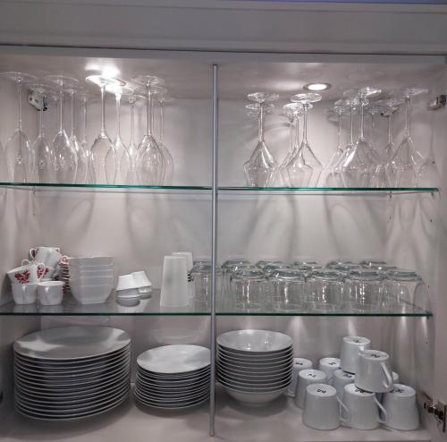 une armoire en verre remplie de assiettes et de verres à vin dans l'établissement Superbe appartement cosy - Plage des minimes, à La Rochelle