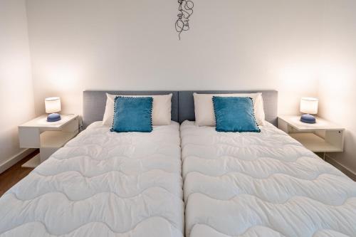 a bedroom with a large bed with blue pillows at HM - HouseMirage in Paço de Arcos