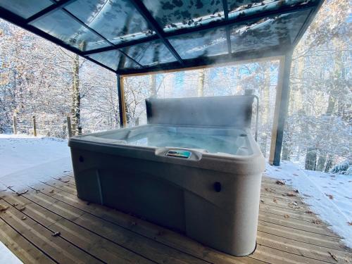 a hot tub sitting on a wooden deck with snow at Le Hygge Chalet Gérardmer-Spa in Anould