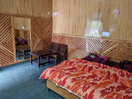 1 dormitorio con 1 cama, mesa y sillas en Shanti guest house chojh en Kasol