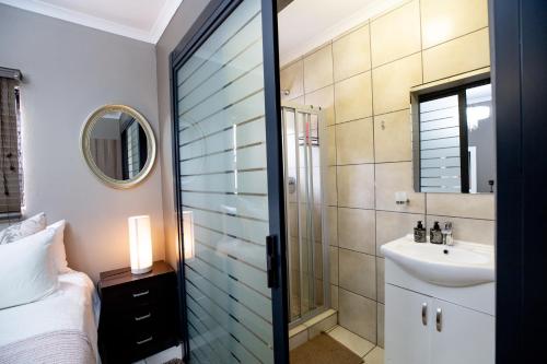 a bathroom with a sink and a toilet and a mirror at URlyfstyle Cottage 10km from OR Tambo Int Airport in Kempton Park