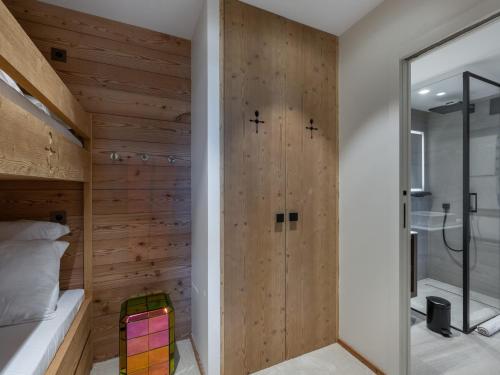 a bedroom with a wooden wall with a shower at Appartement neuf à Courchevel 1850 avec accès direct aux pistes, piscine et SPA - FR-1-564-108 in Courchevel