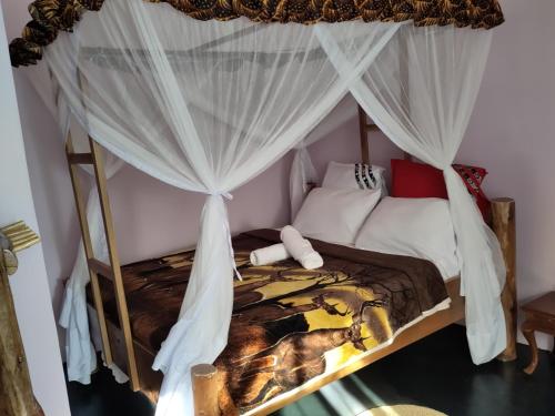 1 dormitorio con cama con dosel y cortinas blancas en Kilimanjaro Scenic Lodge, en Moshi