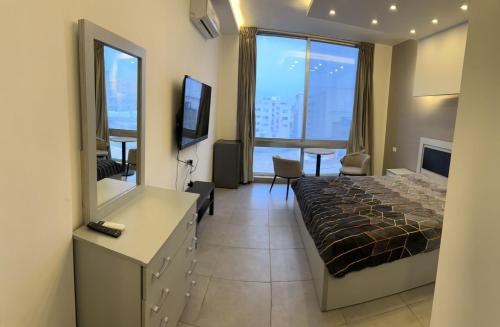 um quarto de hotel com uma cama e uma televisão em Gentle Breeze Studio1 em Amã