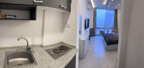 uma cozinha com um lavatório e uma sala de estar em Gentle Breeze Studio1 em Amã