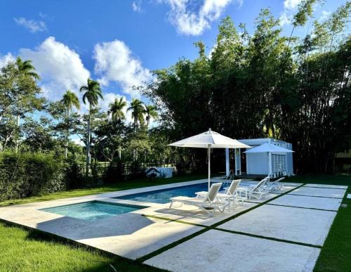 - une piscine avec un parasol et des chaises dans l'établissement Casa Coral - The Coral House, à San Felipe de Puerto Plata