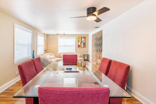 a dining room with a glass table and red chairs at Groovy Getaway! Heated pool! Something different in Cape Coral